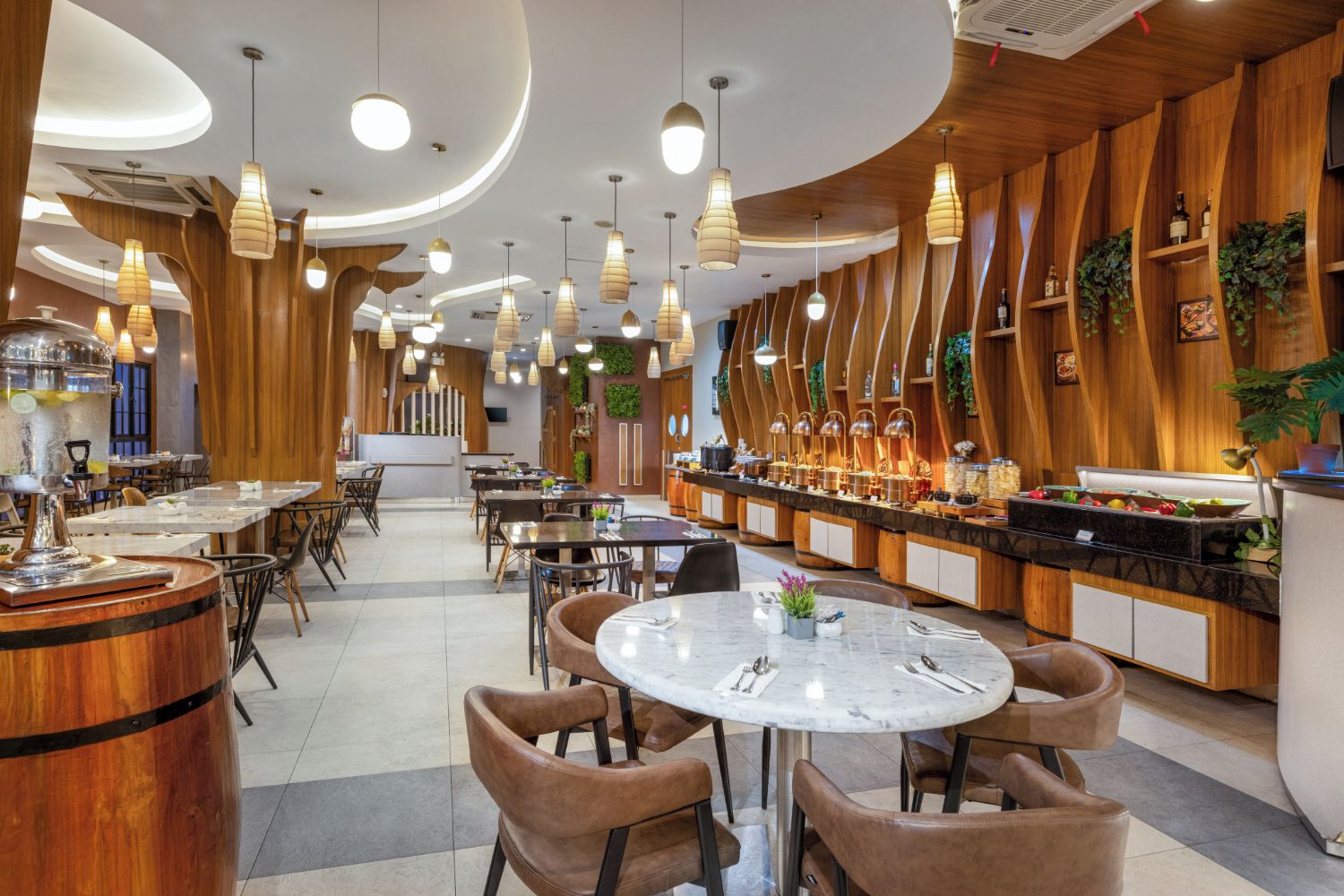 Un intérieur de restaurant moderne avec des tables rondes, des éléments décoratifs en bois et des luminaires suspendus.