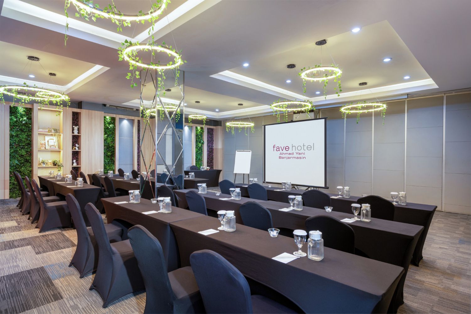 A conference room at Fave Hotel with a long table, chairs, and a projector screen.