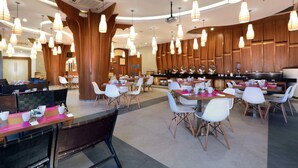 Ein geräumiges Restaurant mit mehreren Essbereichen, Holzvertäfelung und moderner Pendelleuchten.