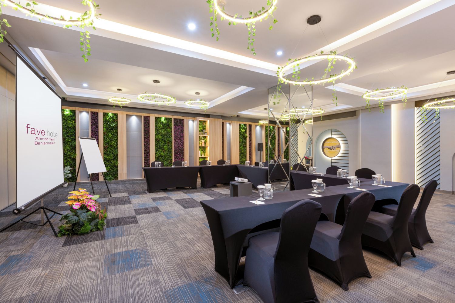 A conference room with a checkered carpet, round tables with chairs, and a projector screen.