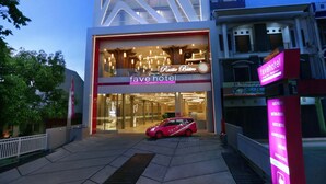 Ein modernes Hotel mit einem gut sichtbaren 'fave hotel' Schild, einem roten Auto vor der Fassade und einem gut beleuchteten Eingang.