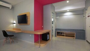 Ein modernes Zimmer mit einer gewölbten Schreibtischplatte, einem Flachbildfernseher, einer roten Akzentwand und einer Sitzecke mit einer Bank und Regalen.
