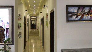 A hotel hallway with a polished floor, framed artwork on the walls, and a potted plant. - Hotel One Super Islamabad (Islamabad)