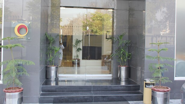 A hotel entrance with a glass door, potted plants, and a visible sign. - Hotel One Super Islamabad (Islamabad)