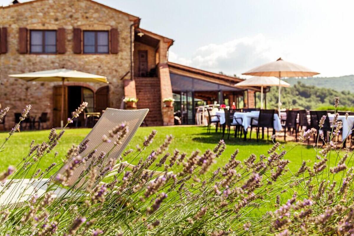 A stone building with outdoor seating and a view of a green landscape.