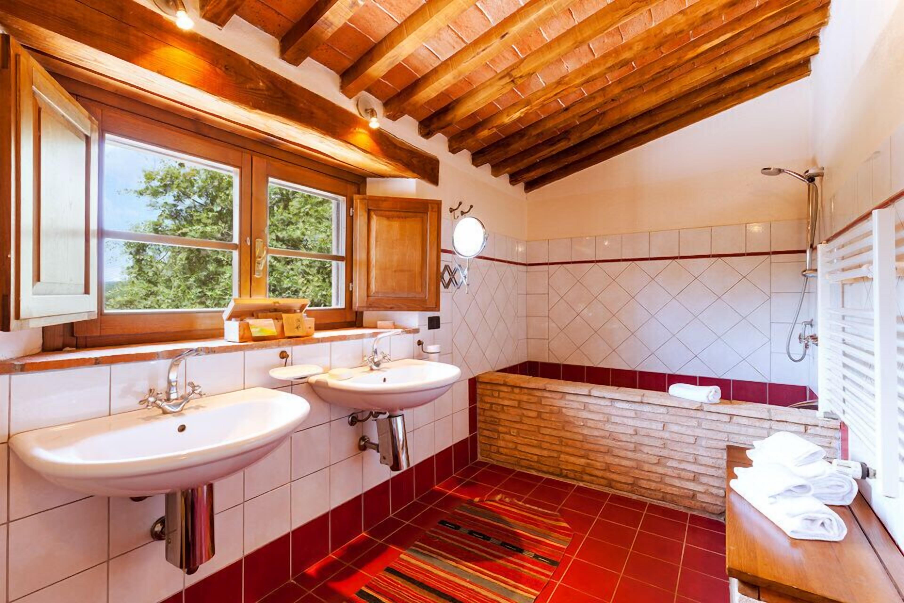 Un baño con dos lavabos, una bañera y una ducha.