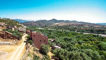 A rural village with traditional buildings, a dirt road, and a mountainous backdrop.