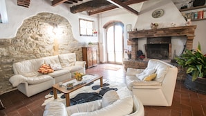 Una sala rústica con paredes de piedra, una chimenea y un rincón de estar acogedor.