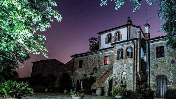 Un edificio de piedra con una escalera central, arcos en las entradas y una pequeña torre.
