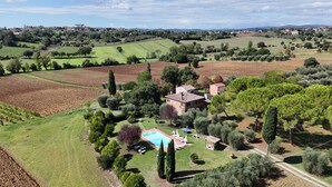 Una villa con piscina, rodeada de olivares y campos.