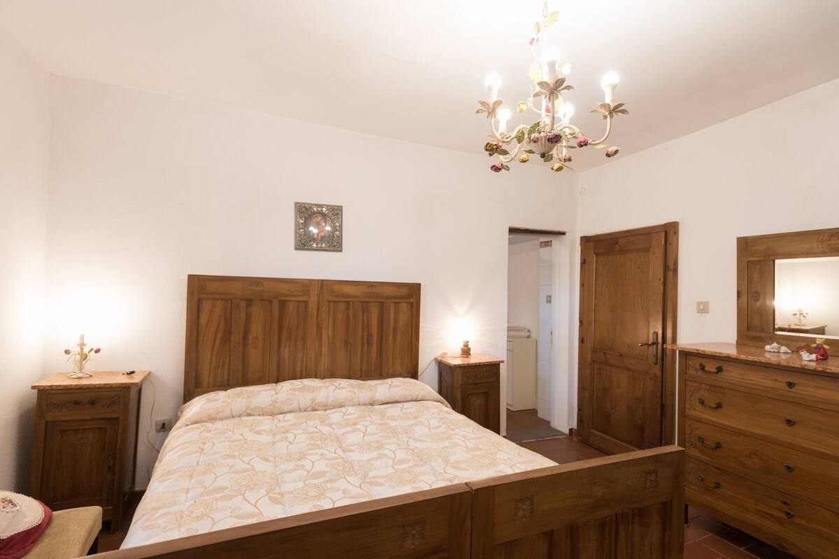 A bedroom with a wooden bed, a nightstand, a dresser, and a mirror.