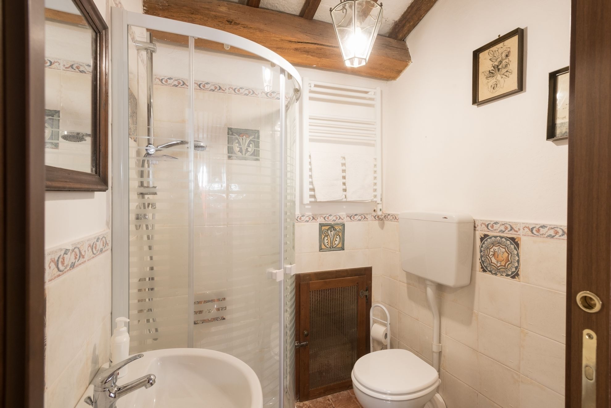 Uma casa de banho com cabine de duche, lavatório e sanita, incluindo porta-papel higiénico.