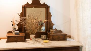 A bathroom vanity with a mirror, a vase of dried flowers, and a small wooden box.