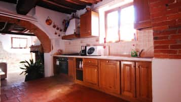 Uma cozinha com armários de madeira, micro-ondas e parede de tijolos.