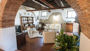 Una sala de estar rústica con arcos de ladrillo visto, una chimenea de piedra y una zona de estar acogedora.