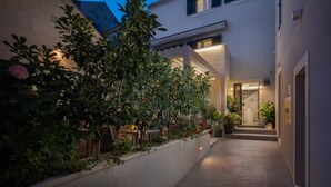 A hotel courtyard with a covered seating area, potted plants, and a pathway leading to the entrance.