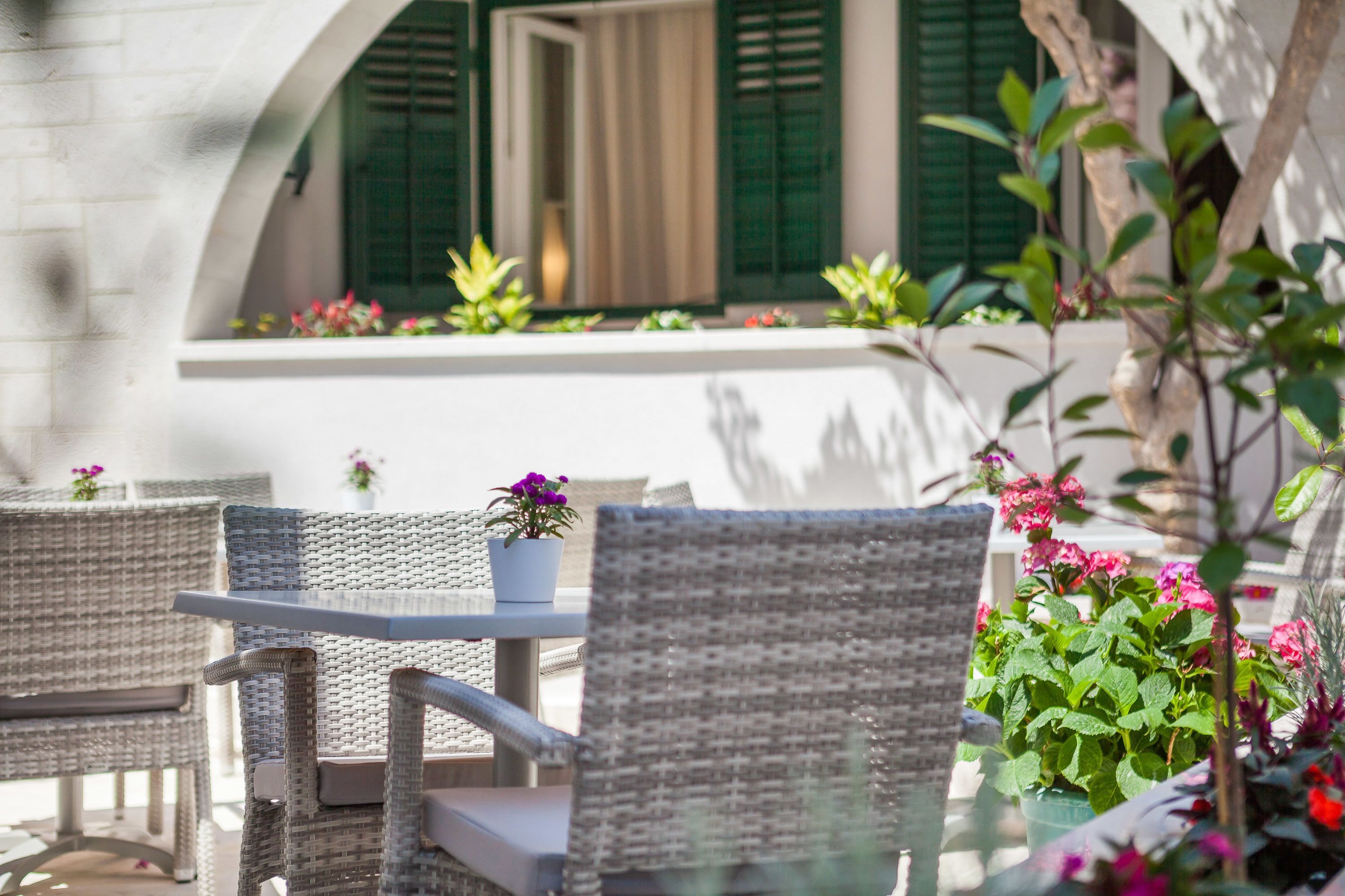 Wicker furniture, a table, and potted plants in an outdoor seating area.