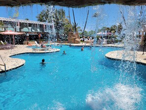 A swimming pool with multiple lanes, lounge chairs, and a lifeguard stand. - Deluxe Beach Resort - HORA RENTALS (Miami Beach)