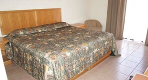 A bedroom with a large bed, a wooden headboard, a chair, and a window with curtains. - Hotel Maria Luisa Inn & Suites (Cadereyta Jimenez)