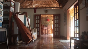 A room with a tiled floor, wooden furniture, a harp, and a thatched roof. - Tanager Rainforest Lodge (Punta Gorda)