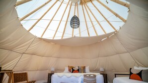 Una carpa espaciosa con una cama, una silla y una mesita.