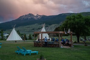 A campsite with teepees, a covered seating area, and a mountain backdrop. - Dreamcatcher Tipi Hotel (Gardiner)