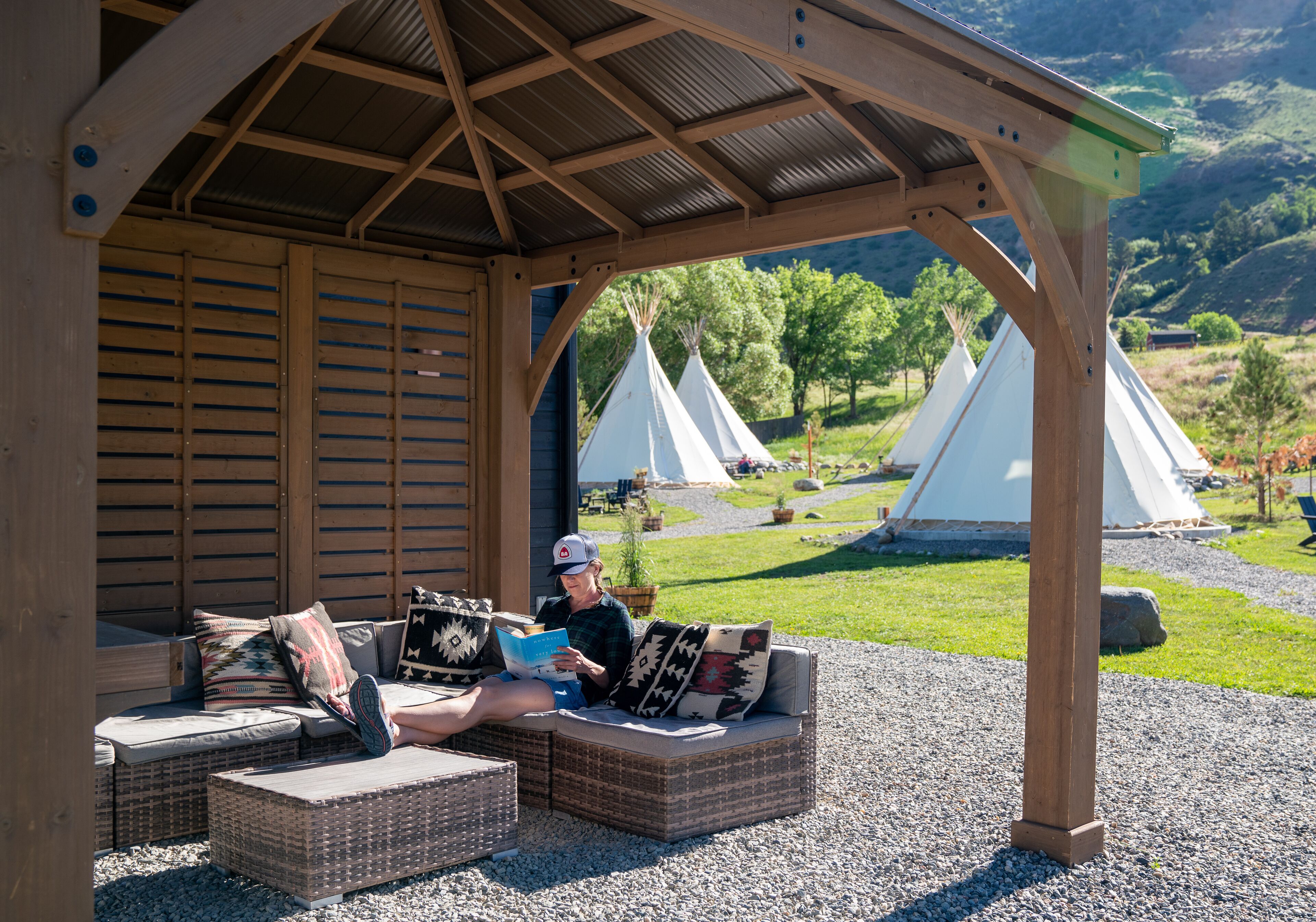 Un espace extérieur abrité, aménagé avec des meubles en osier, offrant une vue sur des yourtes en arrière-plan.