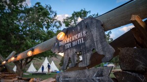 Un letrero de madera con el texto "Dreamcatcher Tipi Hotel" y una lámpara sobre él.