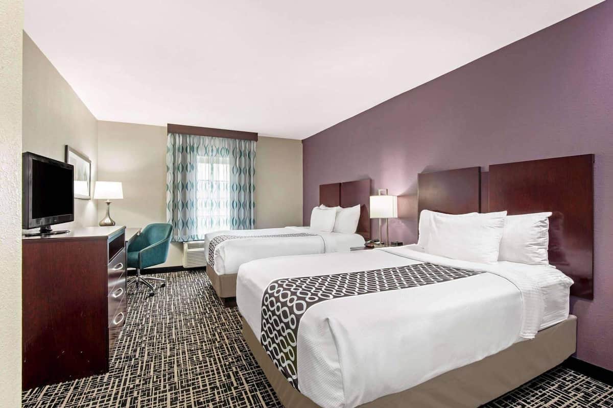 Une chambre d’hôtel avec deux lits, une télévision, un bureau et une chaise.