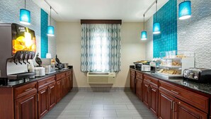 A modern kitchen with wooden cabinets, a built-in coffee station, and a large window with patterned curtains.