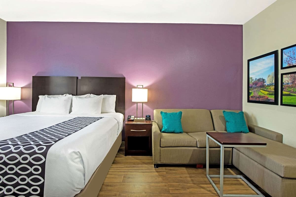 Une chambre d’hôtel avec un lit, un canapé, une table de chevet et une table.