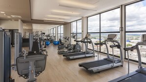 Ein Fitnessstudio mit Laufbändern, Gymbällen und Krafttrainingsgeräten.