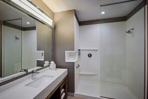 A modern bathroom with a large mirror, two sinks, a shower, and a glass-enclosed shower area. - Courtyard by Marriott Denver Southwest/Littleton (Littleton)