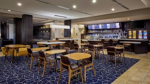 En hotellobby med flera sittgrupper, en bar och ett område där maten visas upp.