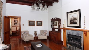 Un salon traditionnel avec une cheminée, deux fauteuils, une table basse et un meuble en bois.