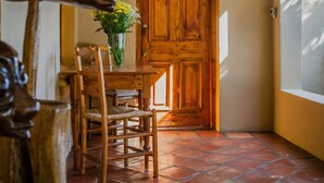 A wooden door with a small window, a tiled floor, and a wooden chair. - Guesthouse LaRachelle (Swellendam)