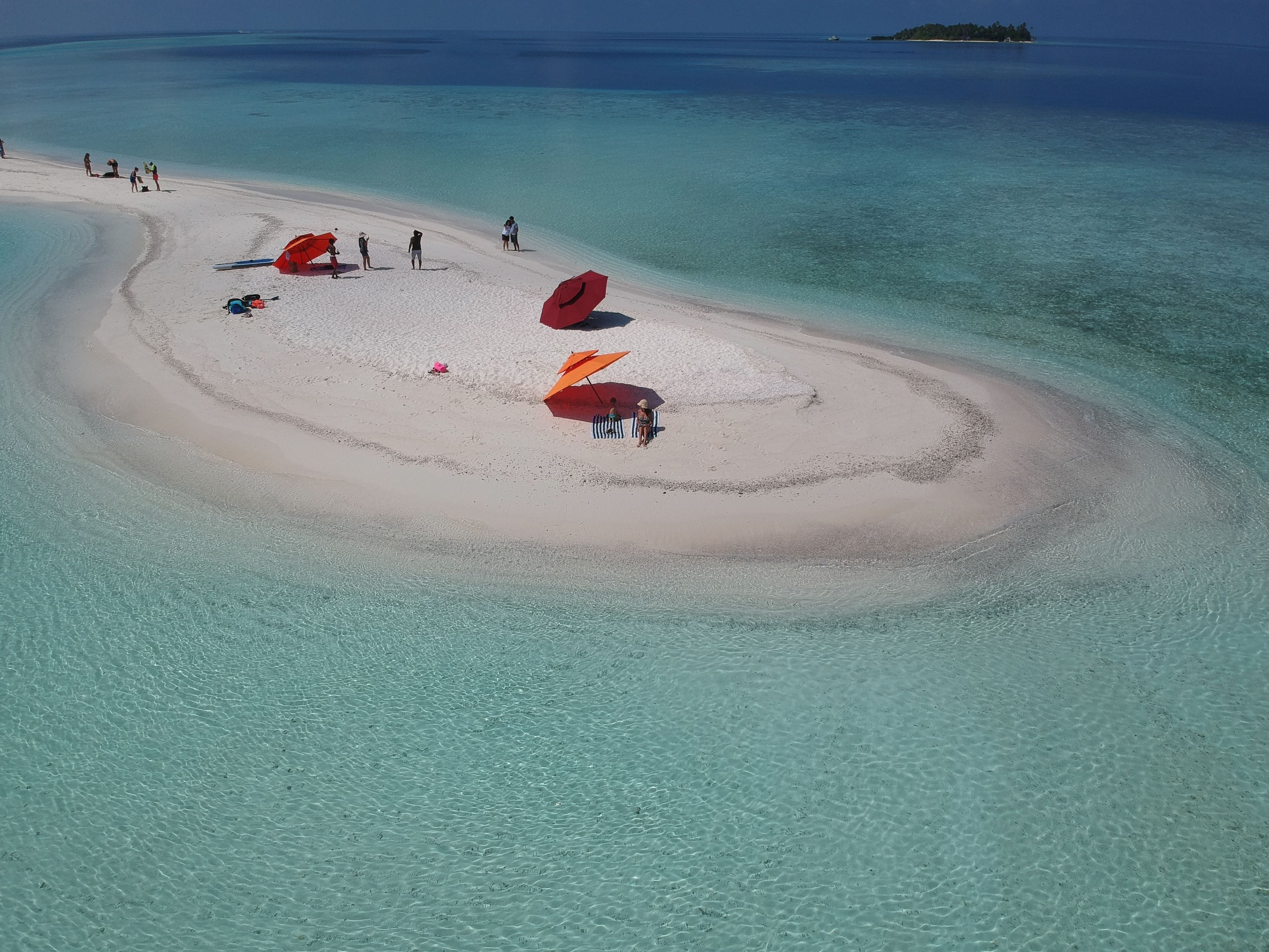 A beach with clear turquoise water and a sandy area with umbrellas.