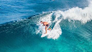 A person surfing on a wave in clear blue water.