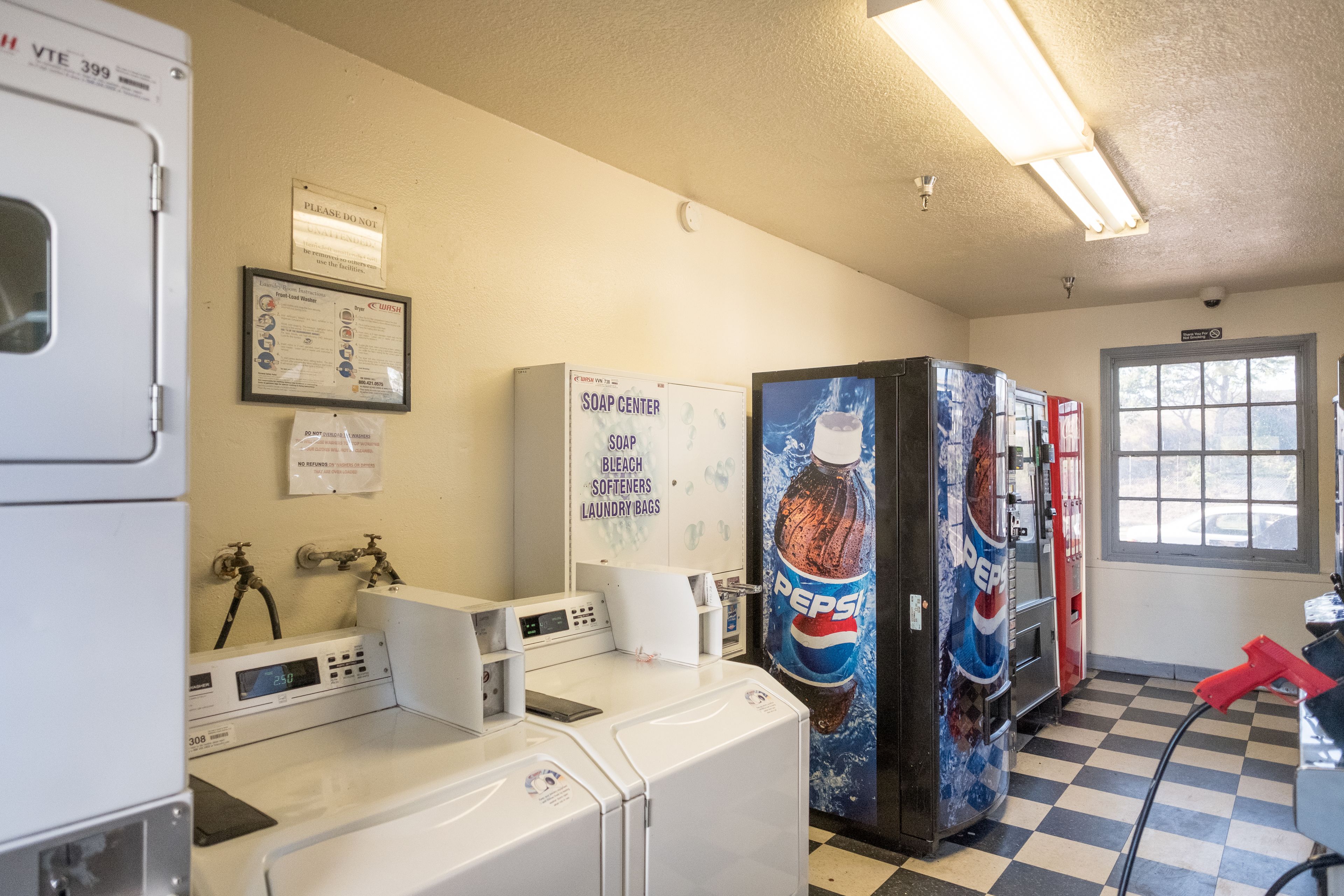 Une laverie équipée de machines à laver, de sèche-linge et d’un distributeur automatique.