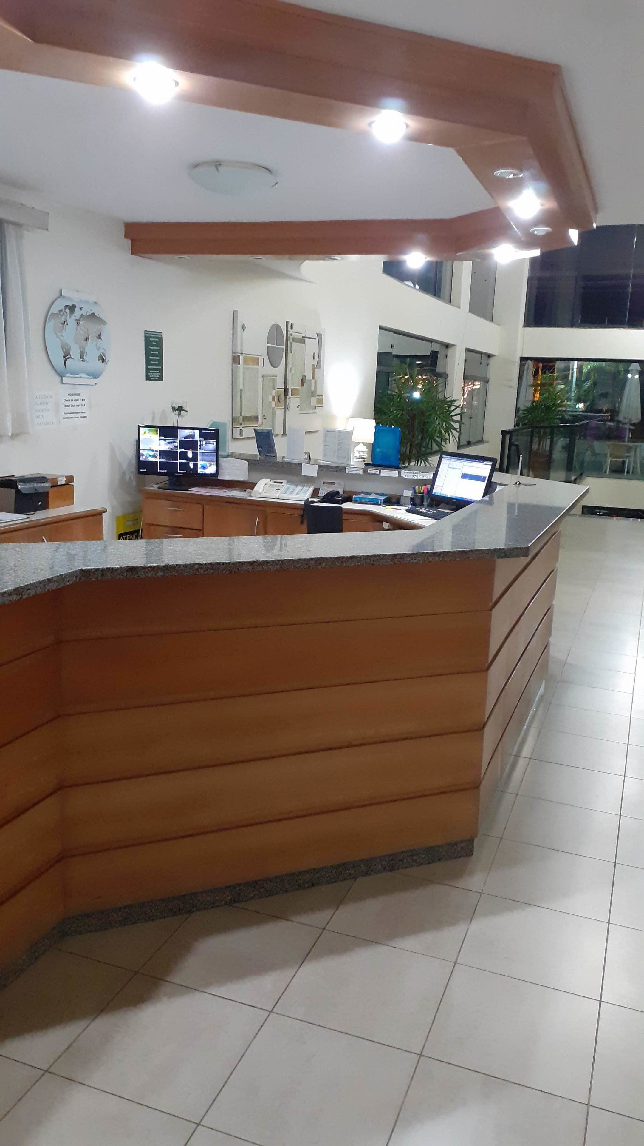 A reception desk with a wooden finish, multiple computer monitors, and a large world map on the wall.