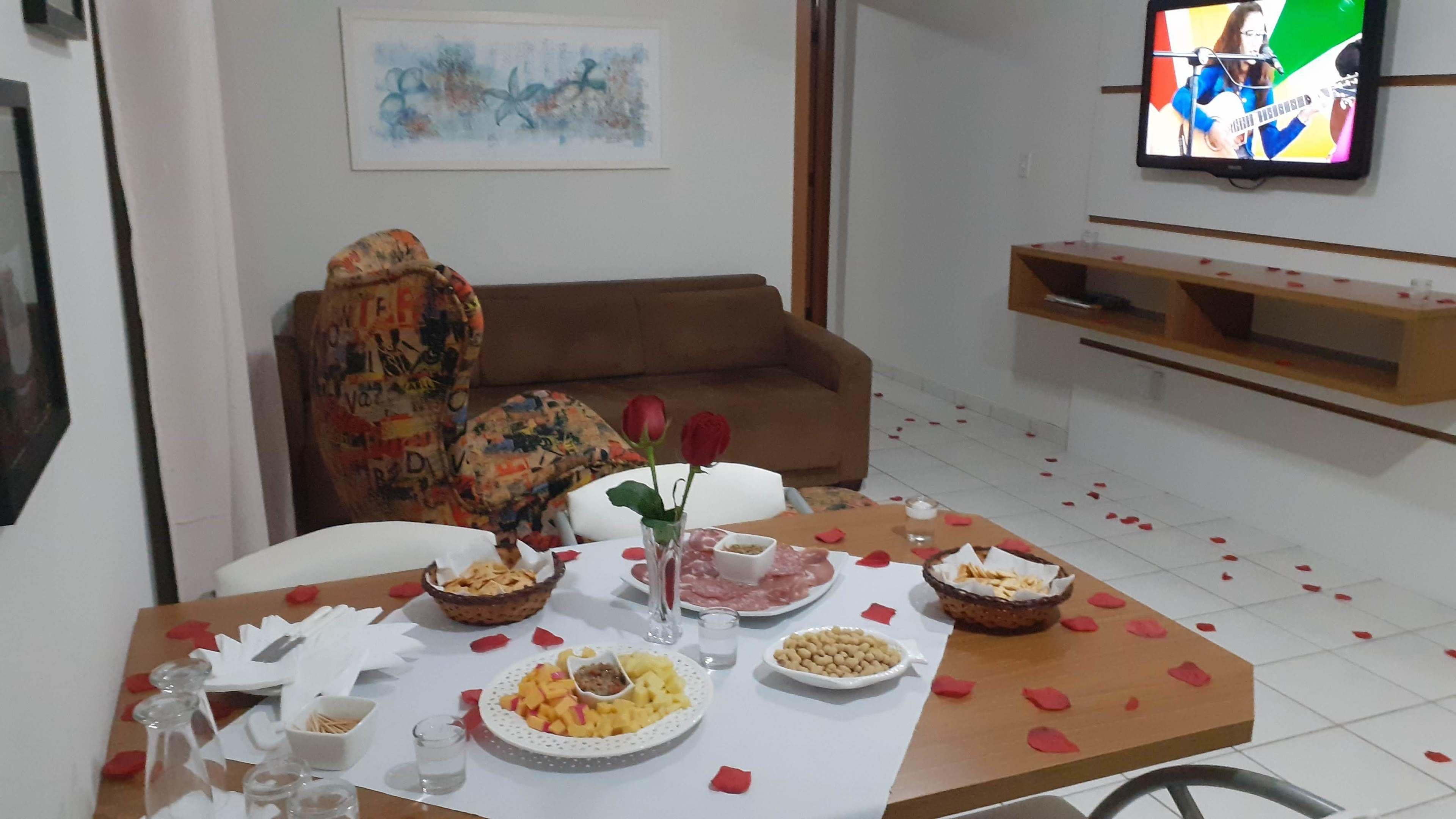 A dining area with a table set for a meal, a sofa, and a television in the background.