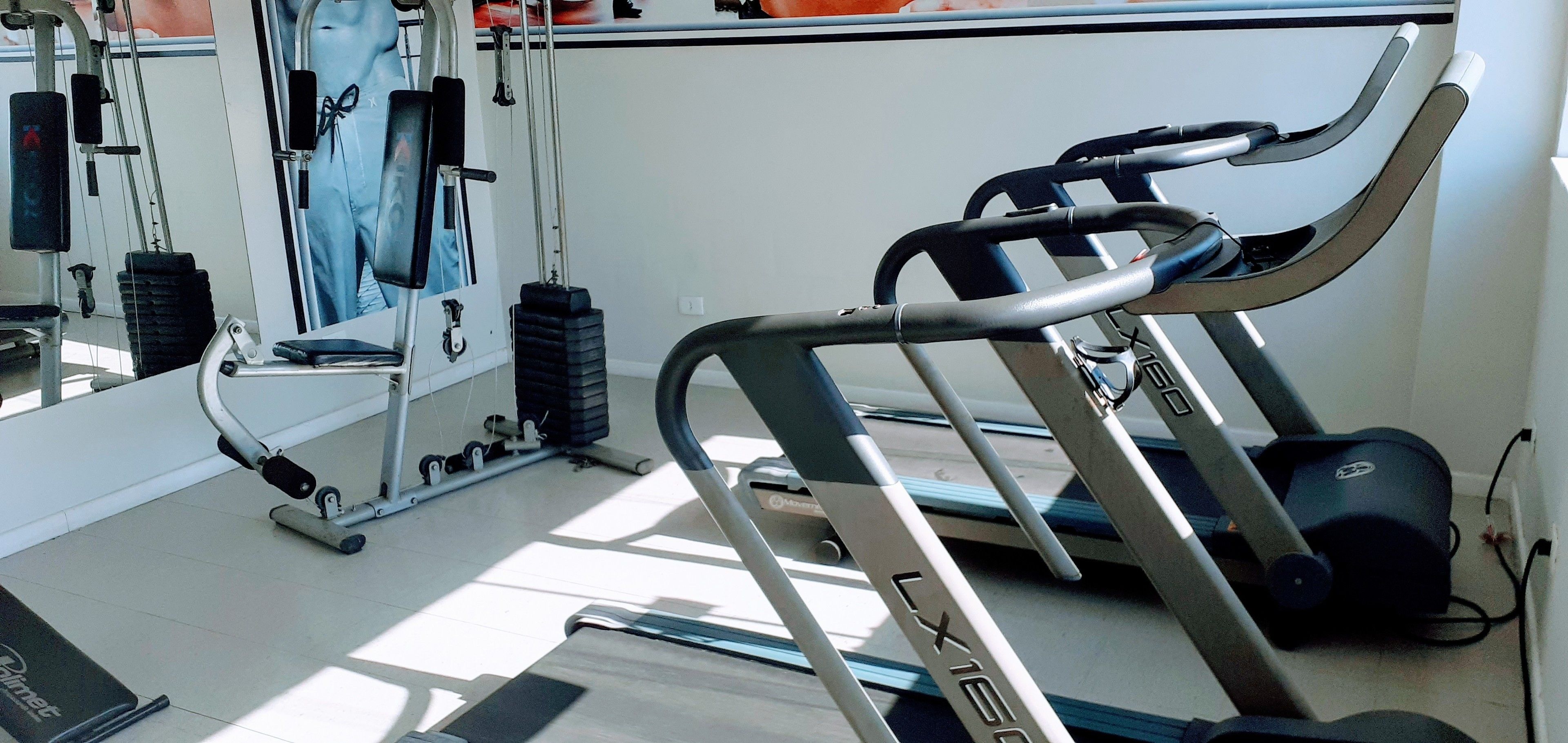 A gym with a treadmill, weights, and a mirror.