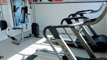 A gym with a treadmill, weights, and a mirror.