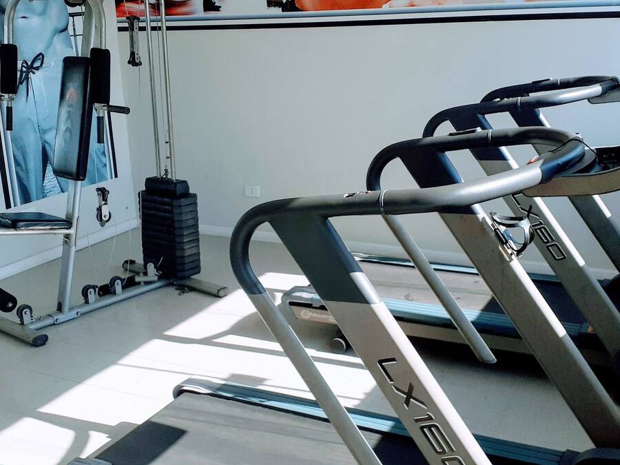 A gym with a treadmill, weights, and a mirror.