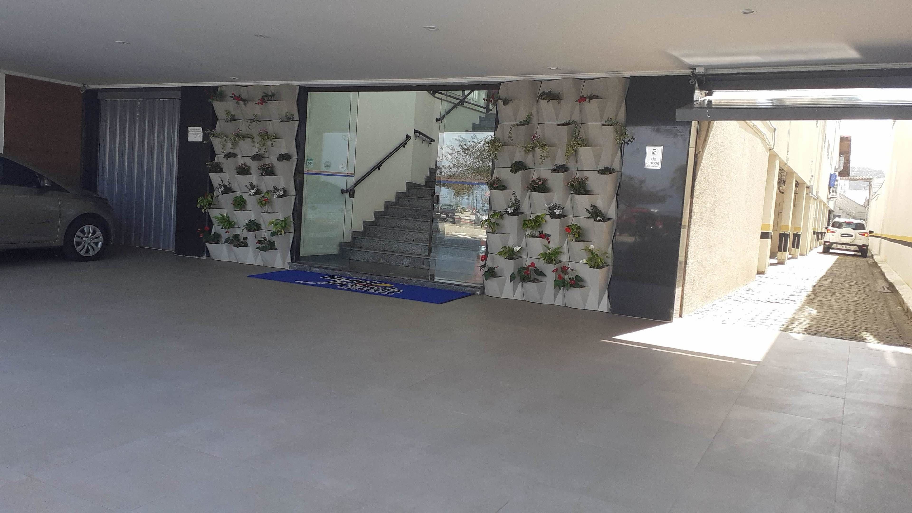 A modern building entrance with a staircase leading to a second floor, a car parked outside, and a blue mat at the entrance.