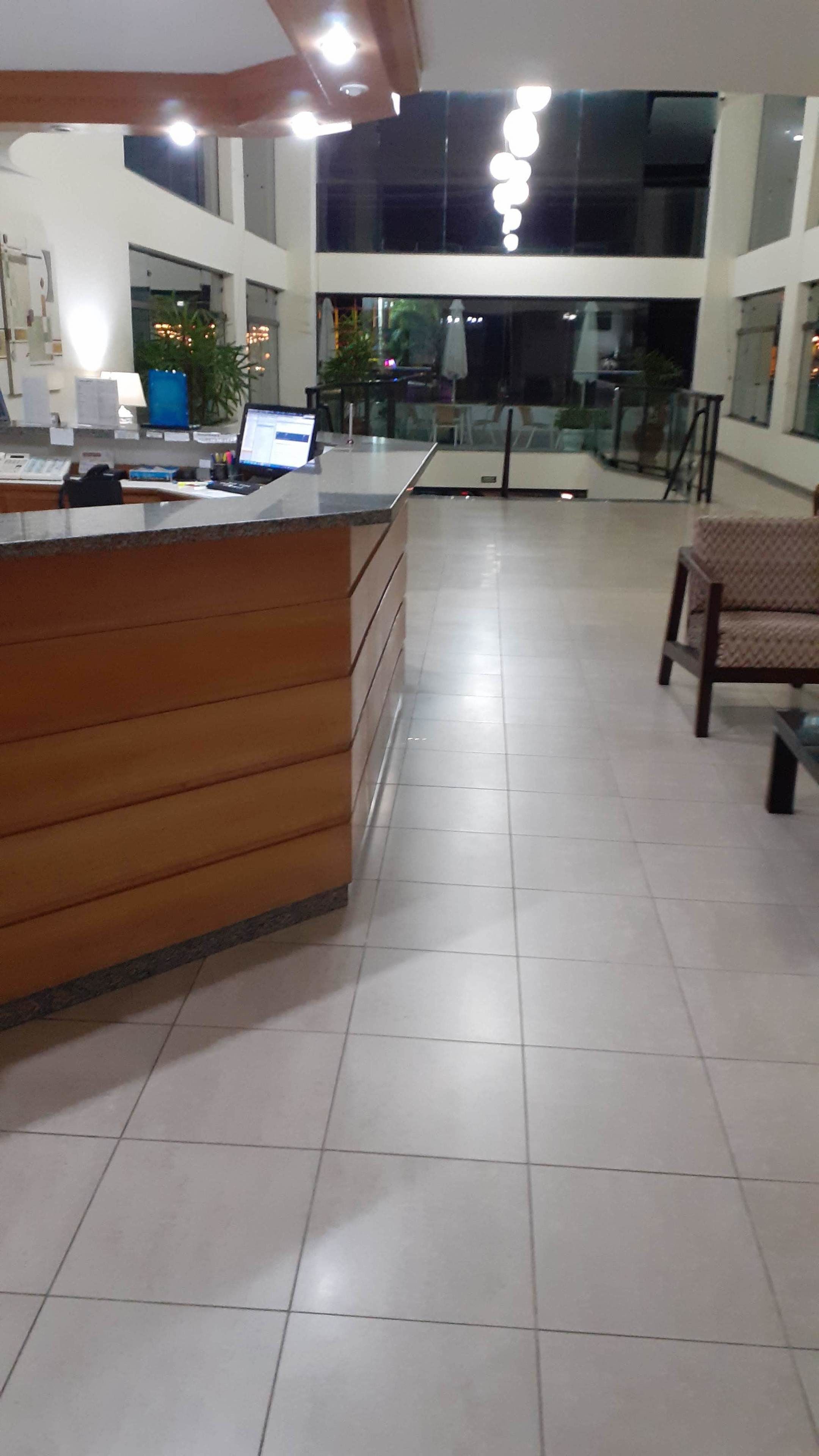 Amplia recepción con mostrador de madera, una computadora portátil y una planta en maceta.