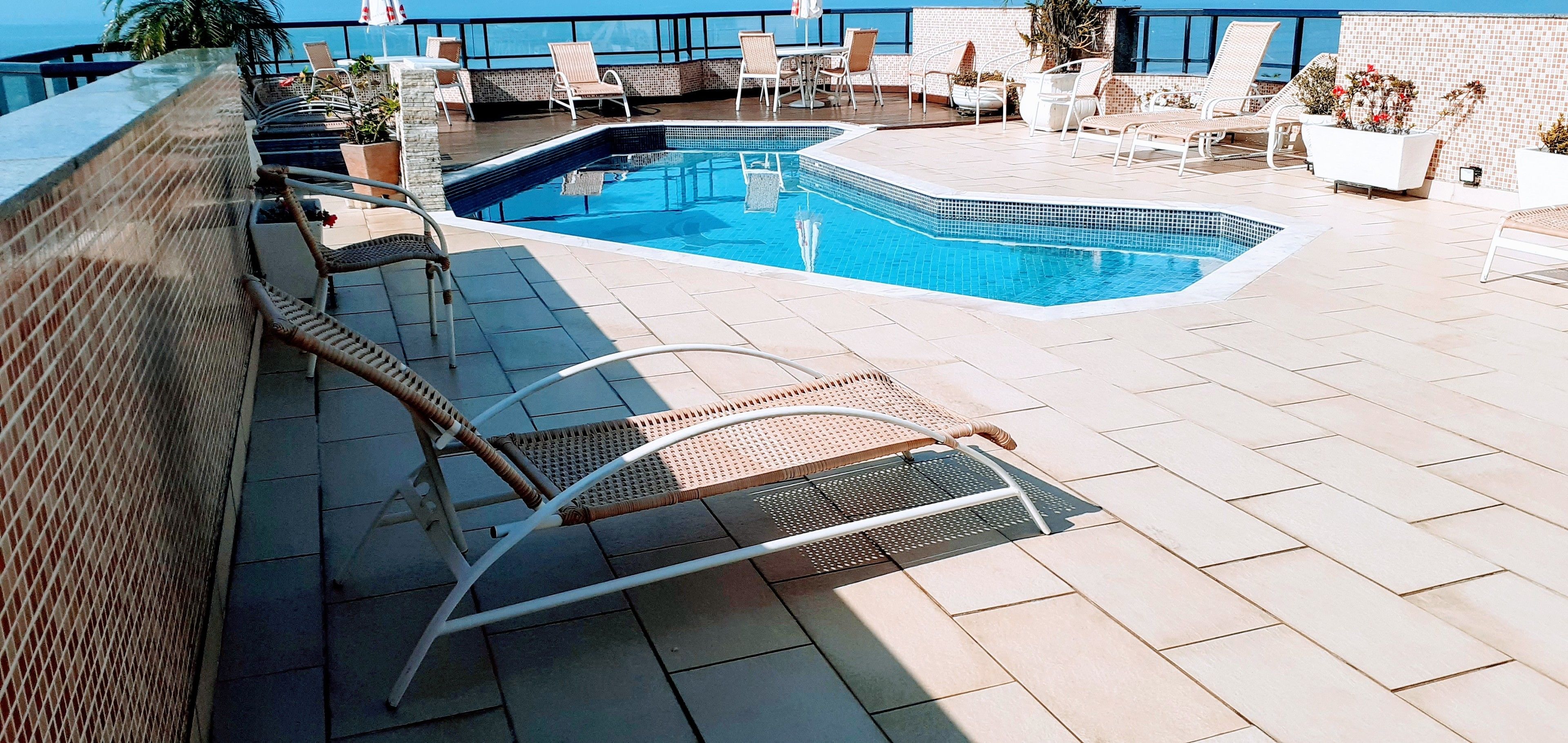 Un espace piscine aménagé sur le toit, avec des chaises longues, une petite piscine et une vue sur l’océan.