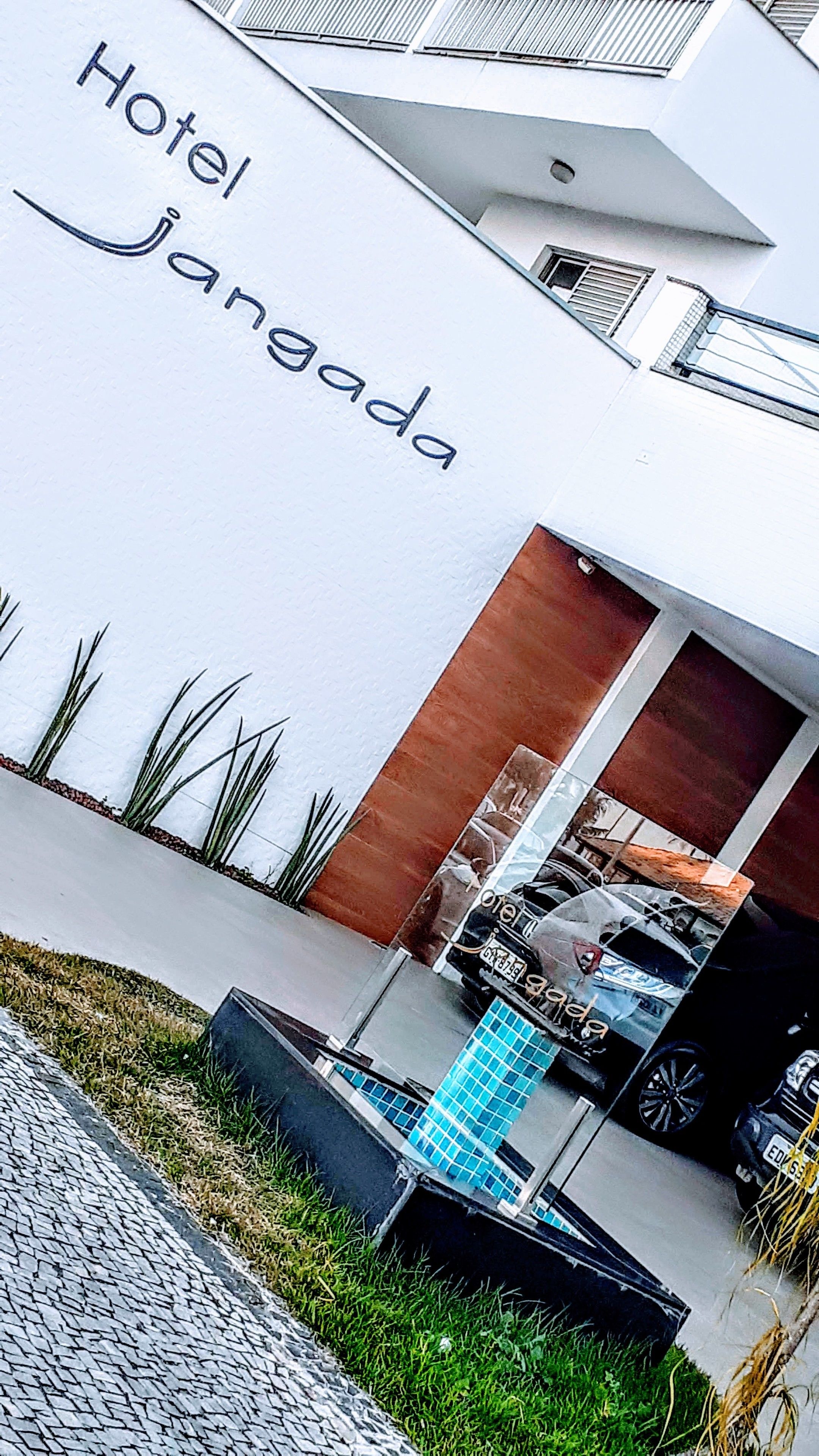 Een modern hotel genaamd 'Hotel Janaada' met een strak, wit gevel en een opvallende entree.