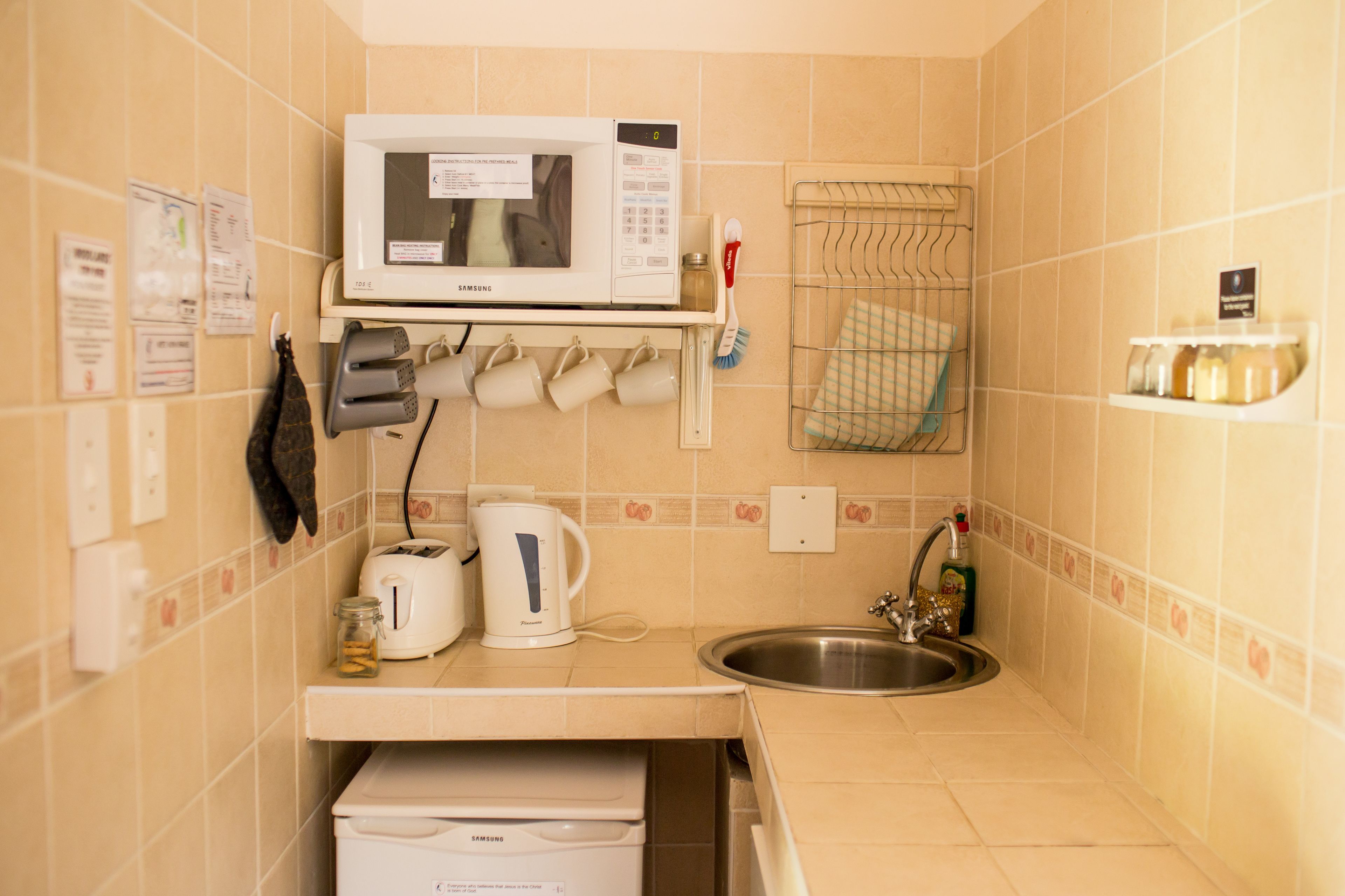 A compact kitchen with a microwave, toaster, and sink.
