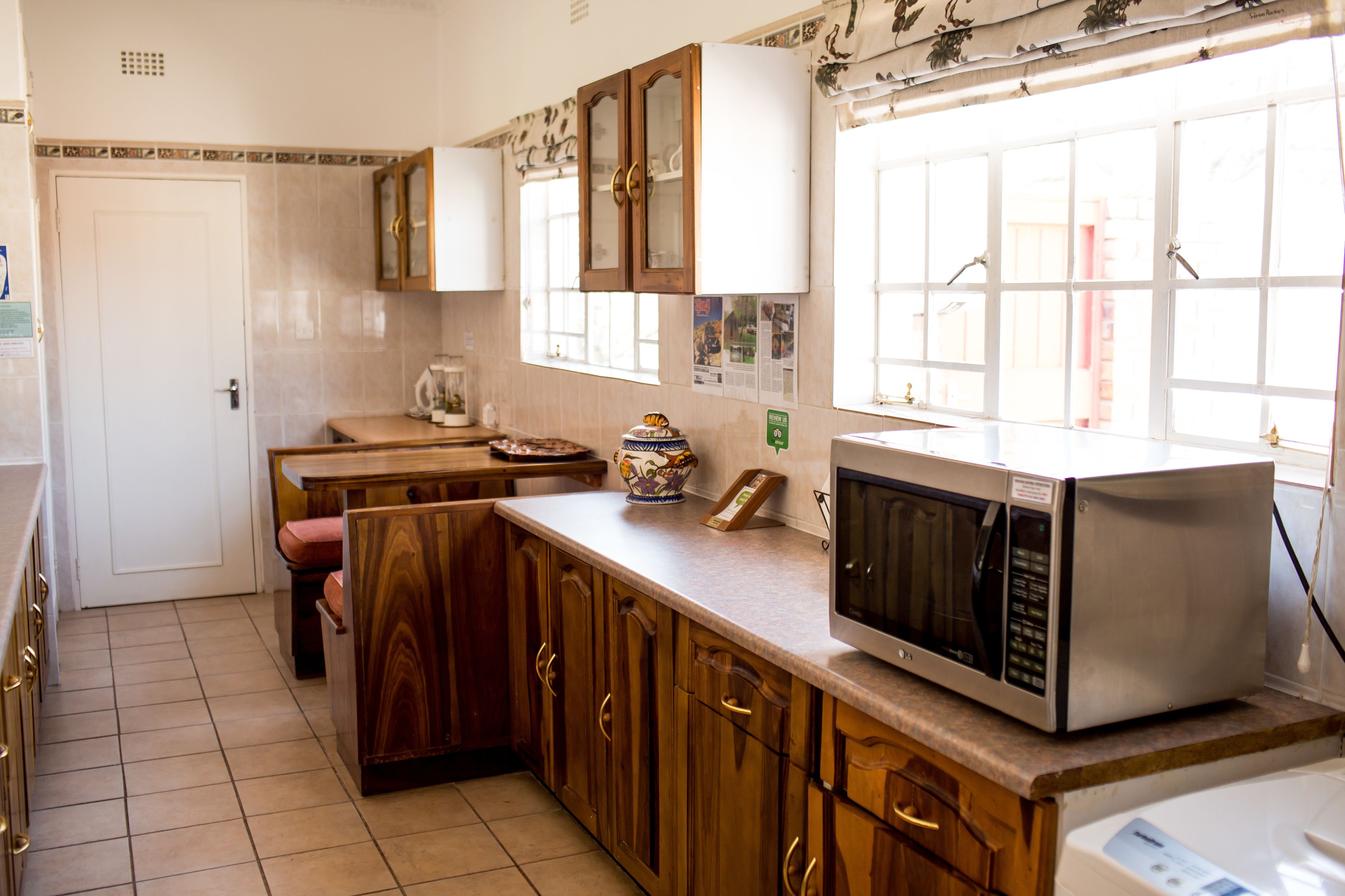 Una cocina con armarios de madera, microondas y ventana con vistas.